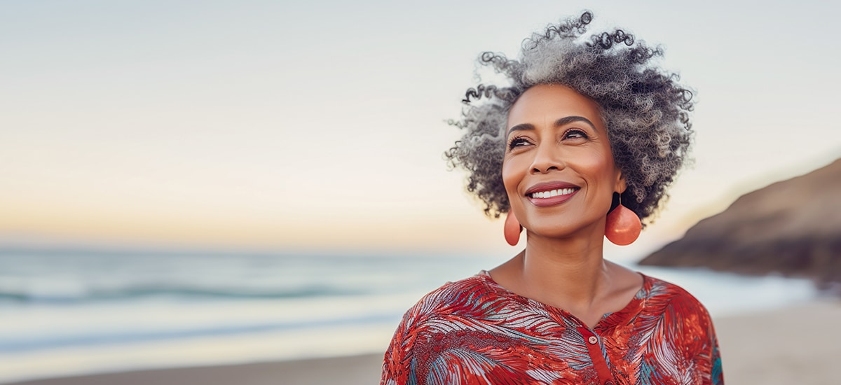 Mature woman on a beach following hearing aid maintenance tips during the summer