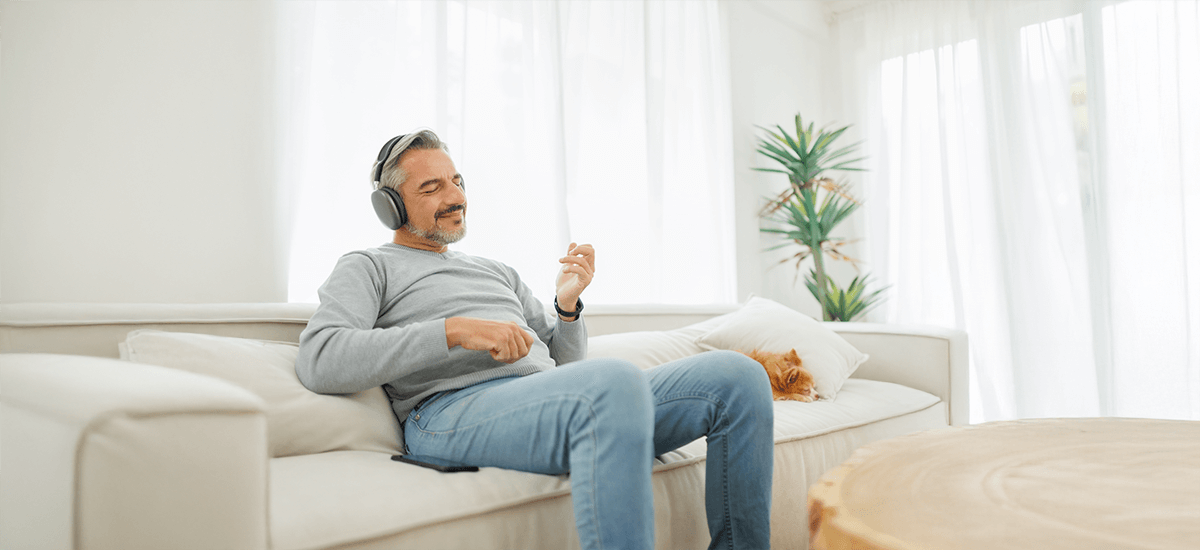 Man unwinds with music on sofa beside resting cat in a living room